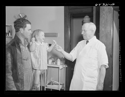 Chaffee, Missouri. Doctor giving little girl a stick of candy. She has just received an injection of anti-hydrophobia v…